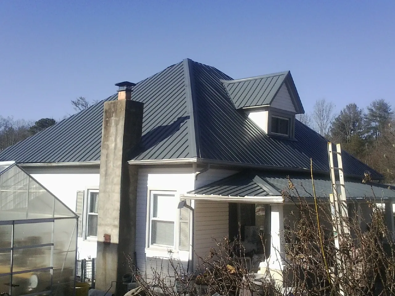 Dark blue standing seam metal roof on a white farmhouse with dormer — Slate & Tile Roof Repair by Roofing Brothers in Martinsburg