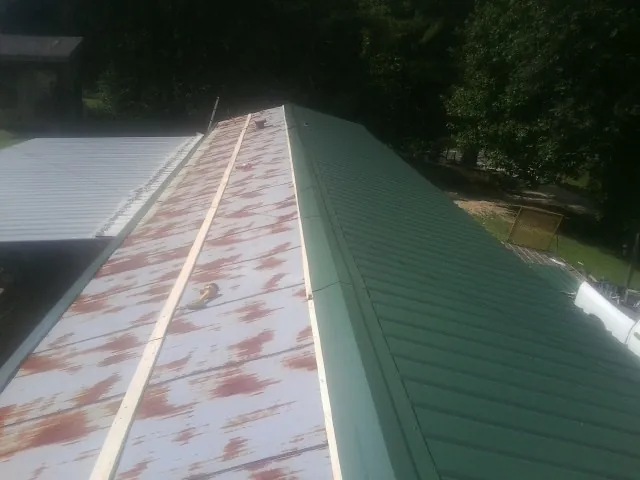 Old rusted panels beside newly installed green metal roofing — Wind Damage Roof Repair by Roofing Brothers in Martinsburg