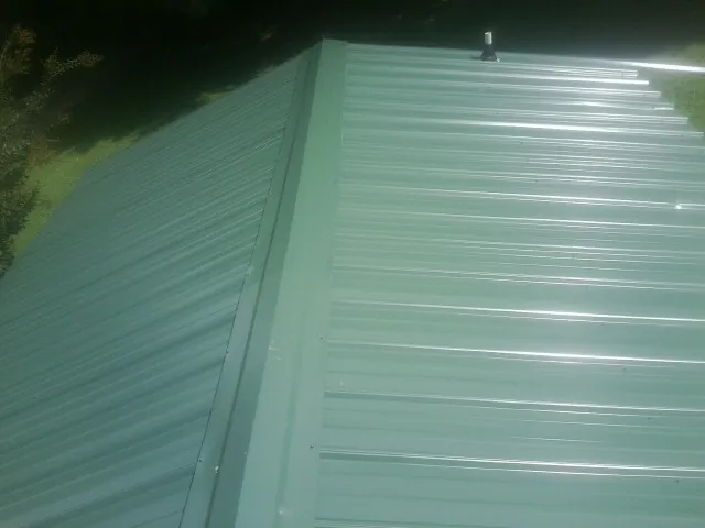 New green metal panels meeting at the ridge of a roof — Flat Roof Repair work by our crew in Martinsburg