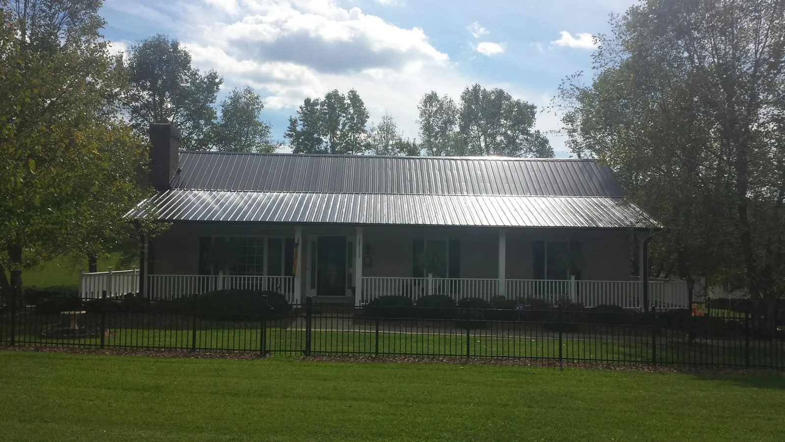 Gray metal roof on a brick ranch with a full width front porch — Gutter Guard Installation work by our crew in Martinsburg