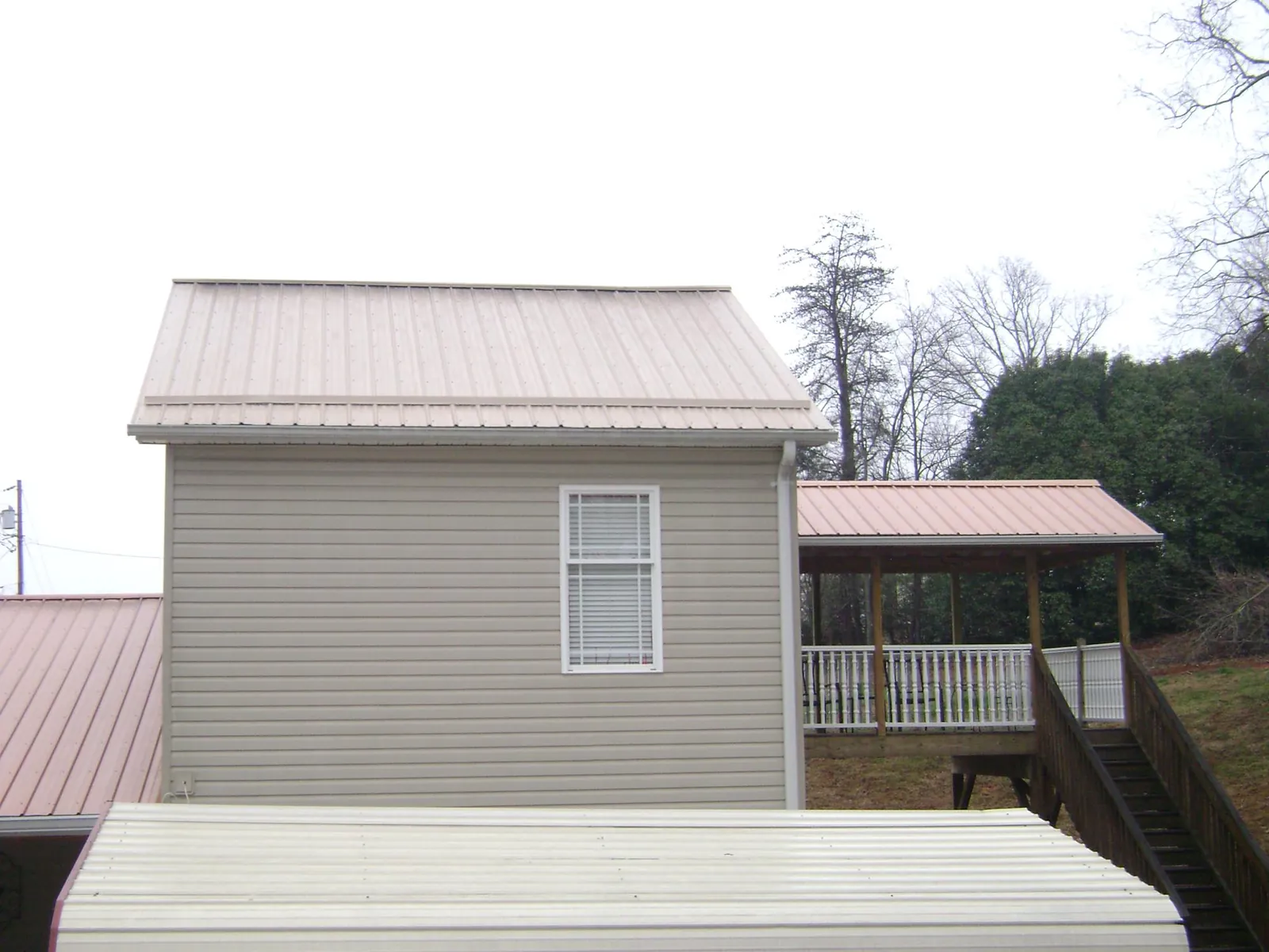 Tan metal roofs on a two story addition and attached porch, from a Roof Replacement job in Martinsburg